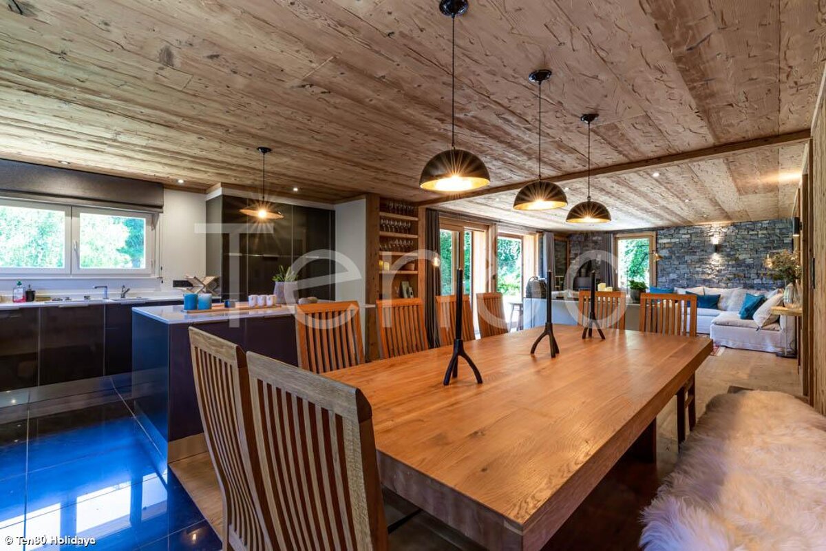 A dining room with a large wooden table and chairs
