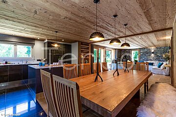 A dining room with a large wooden table and chairs