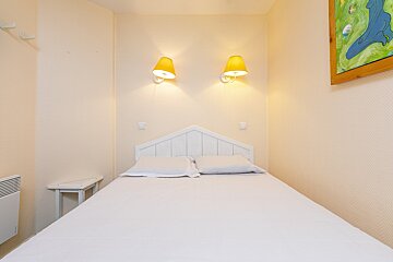 A small bedroom with a bed and two lamps