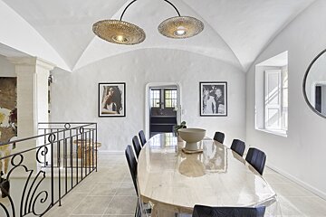 A dining room with a table and chairs and pictures on the wall