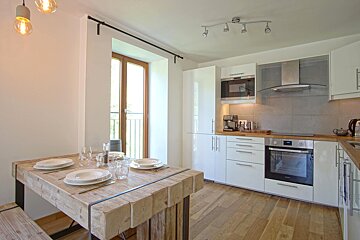 A kitchen with white cabinets and a wooden table
