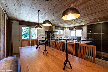 A kitchen with a wooden ceiling and a wooden table