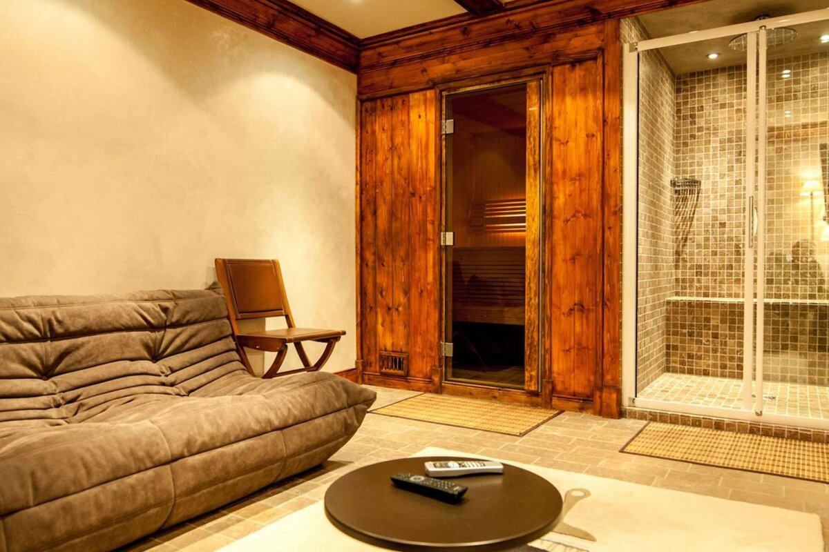 A living room with a couch and a remote in front of a wooden sauna