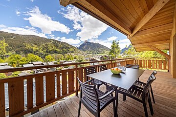 A balcony with a table and chairs and a view of mountains
