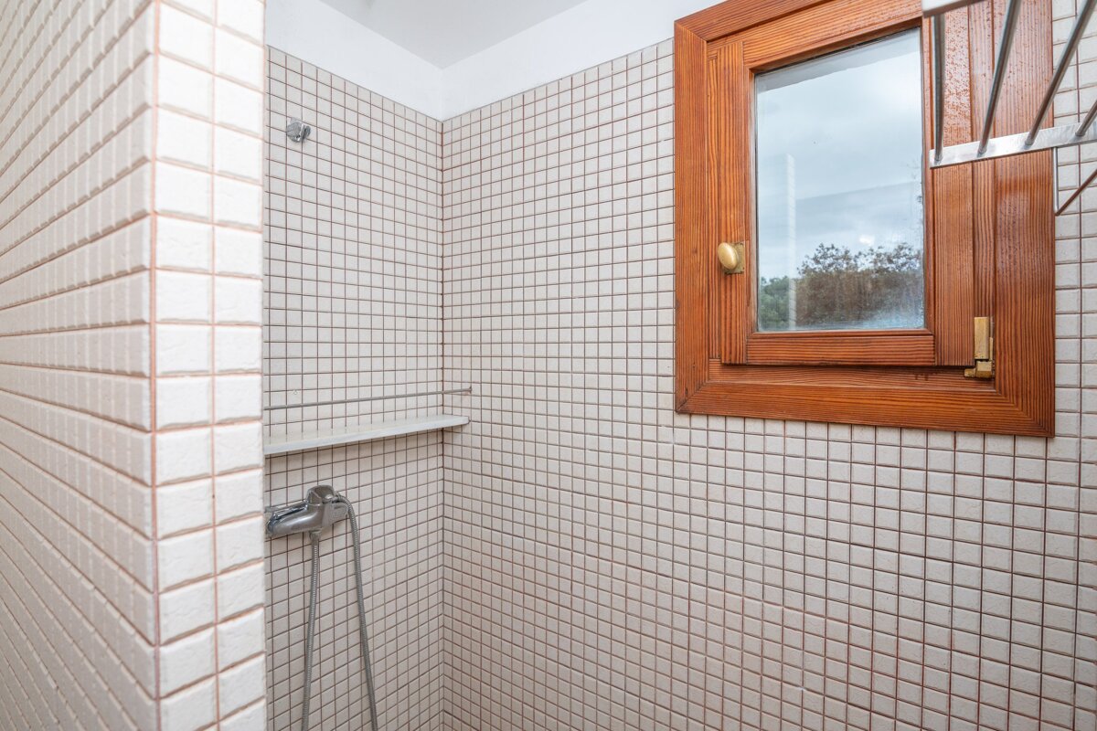 A bathroom with white tiles and a wooden window