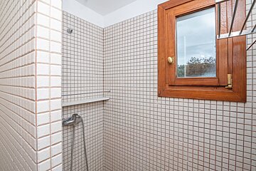 A bathroom with white tiles and a wooden window