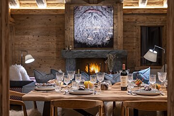 A bottle of wine sits on a table in front of a fireplace
