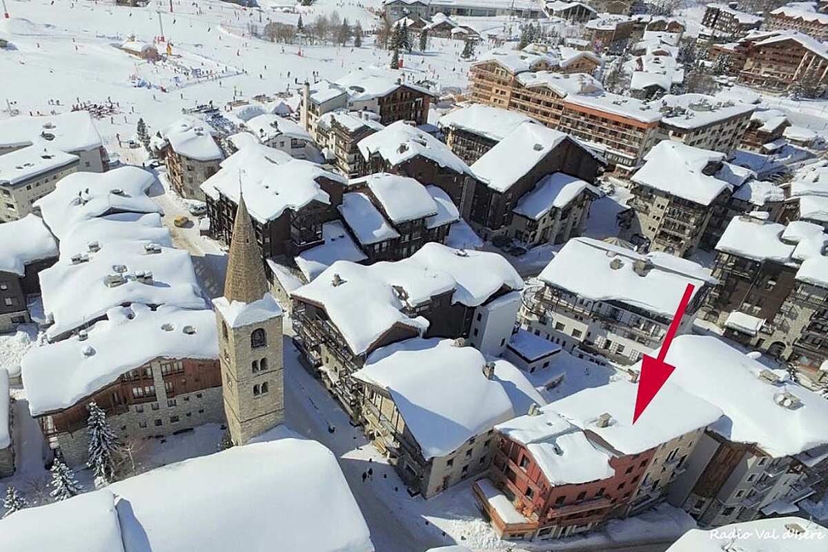 An aerial view of a snowy town with a red arrow pointing to a building