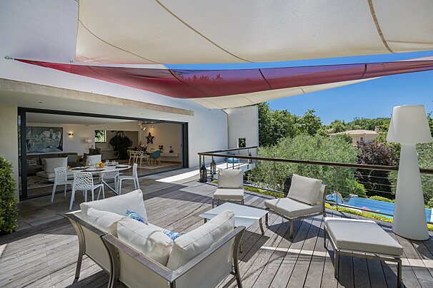 A deck with a lot of furniture and a red and white canopy