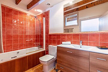 A bathroom with red tiles and a toilet