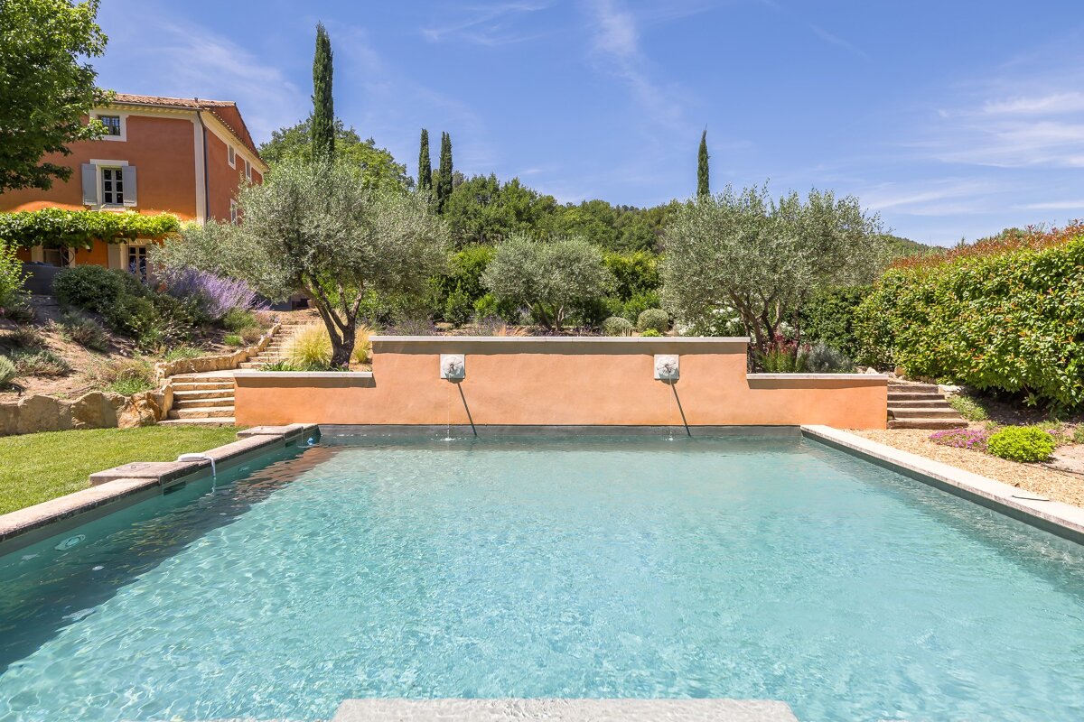 A large swimming pool with a house in the background