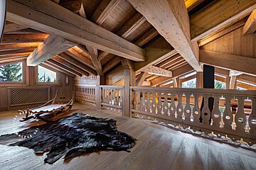 A sleigh sits on a wooden floor next to a wooden railing