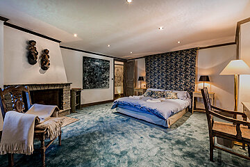 A bedroom with a large bed and a fireplace