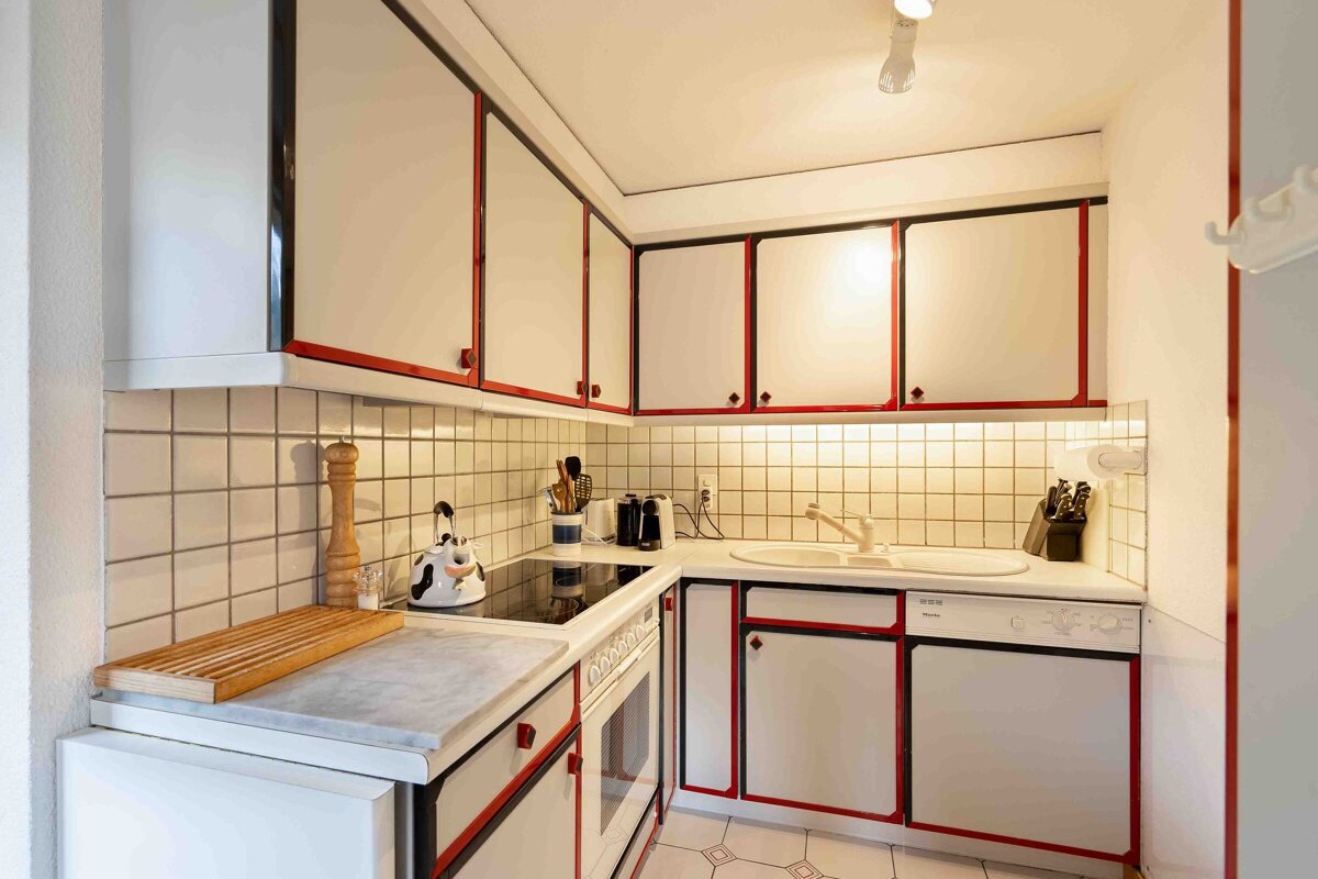 A kitchen with red and white cabinets and a siemens dishwasher