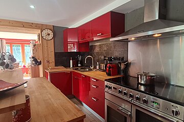 A kitchen with red cabinets and a clock on the wall