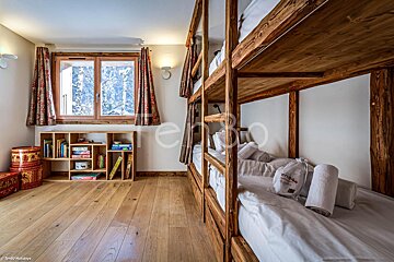 A bedroom with bunk beds and a shelf with books and games