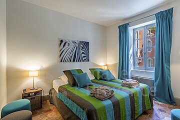 A bedroom with blue curtains and a zebra painting on the wall