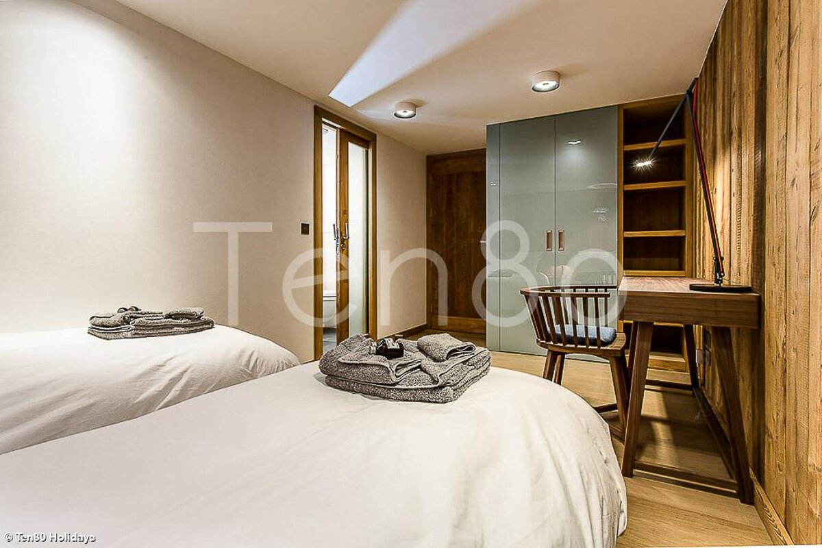 A bedroom with two beds and a desk that says ten80