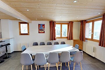 A dining room with a table and chairs and a painting on the wall