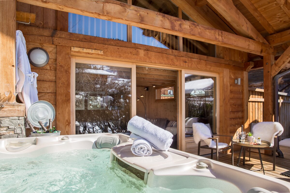 A hot tub sits outside of a wooden cabin