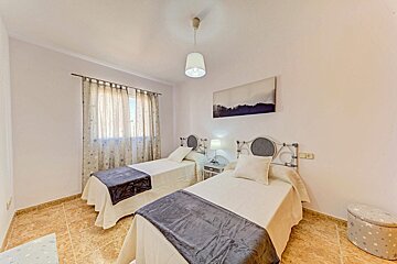 A bedroom with two beds and a painting on the wall