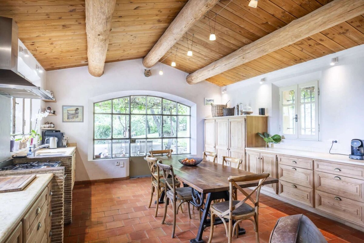 A kitchen with a wooden table and chairs and a large window