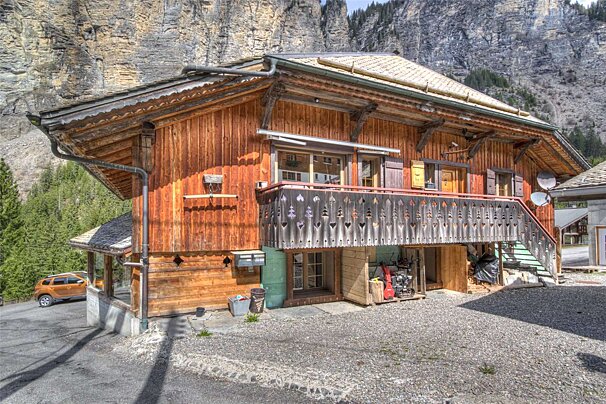 A wooden house with a balcony and a mountain in the background