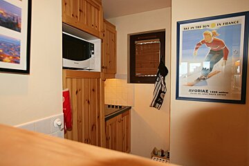 A cozy kitchen area featuring wooden cabinets, a microwave, and stovetop. A 