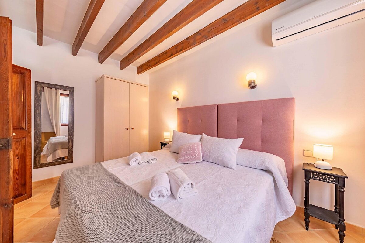 A bedroom with a pink headboard and white sheets