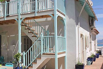 A white building with a blue staircase leading up to the second floor