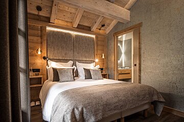 A bedroom with a large bed and a television on the wall