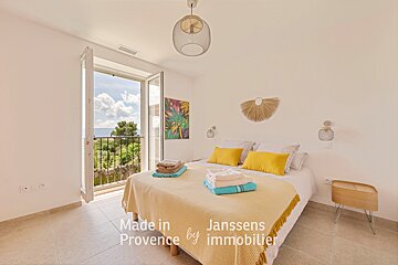 A bedroom with a bed and a balcony made in provence by janssens immobilier