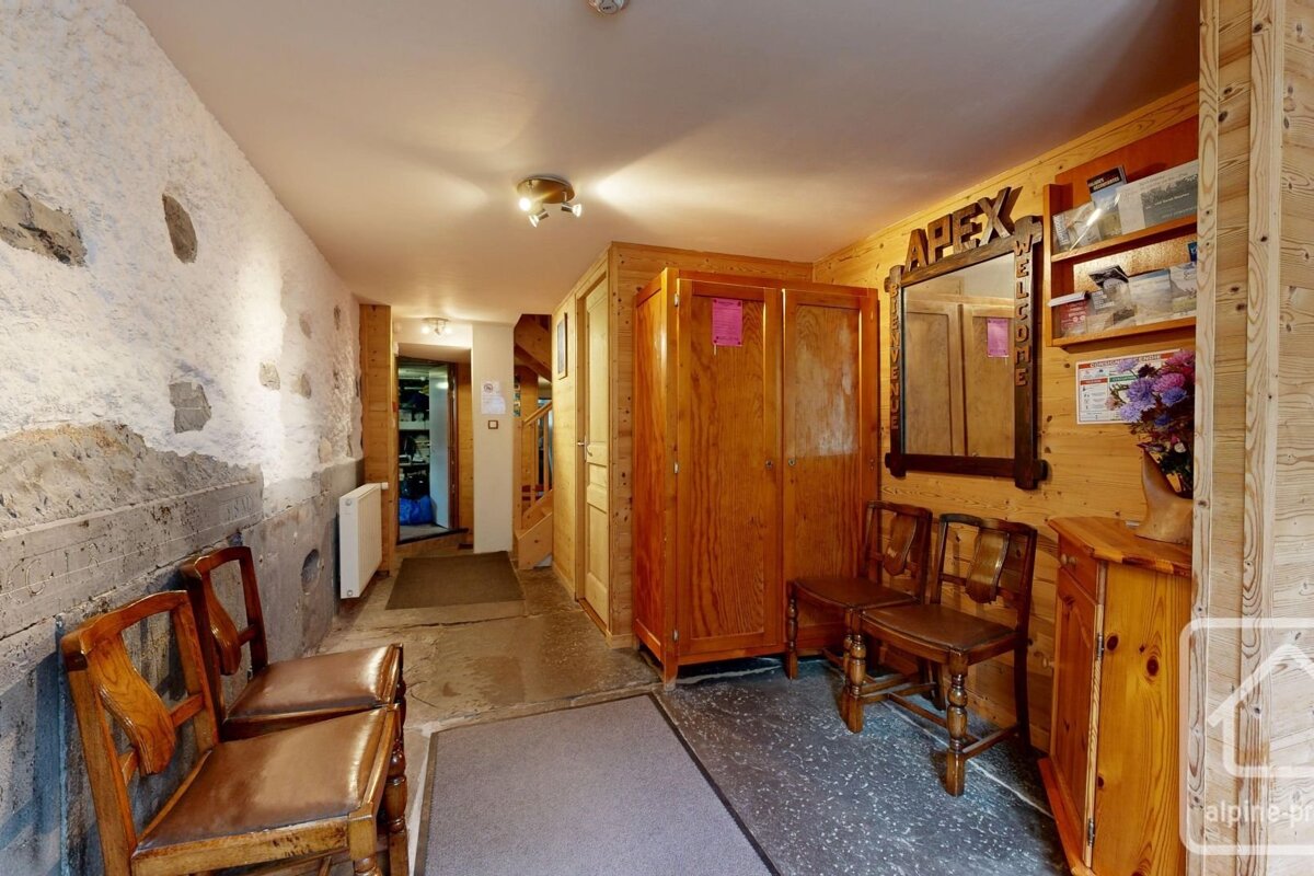 Rustic wooden entryway with matching chairs, an armoire, stone accent wall, mirror, and shelves.