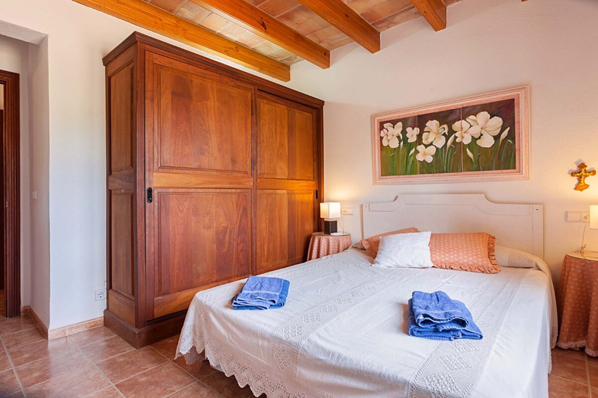 A bedroom with a painting on the wall above the bed