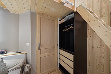 A bedroom with a wooden staircase and a closet underneath it