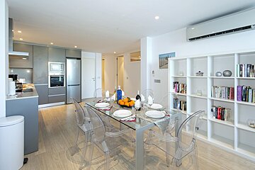 A dining room table with clear chairs and a bottle of wine on it