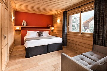 A bedroom with a bed and a chair in it