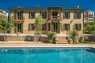 A large house with a swimming pool in front of it
