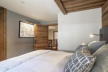 A bedroom with a painting on the wall above the bed