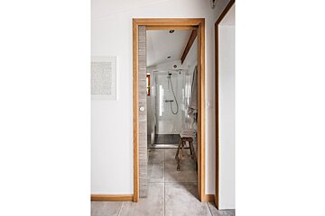 A bathroom with a walk in shower and a stool