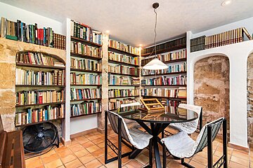 A library with a table and chairs and a fan