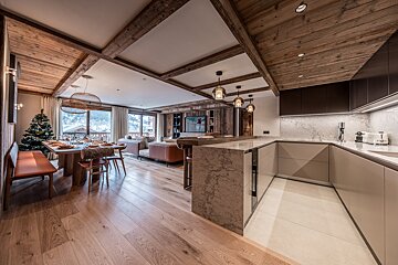 Elegant open-plan lodge with dining area (Christmas tree), living room, and modern kitchen. Features rich wood accents, mountain views, and cozy ambiance.