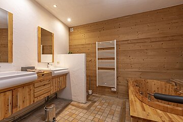 A bathroom with two sinks and a wooden tub