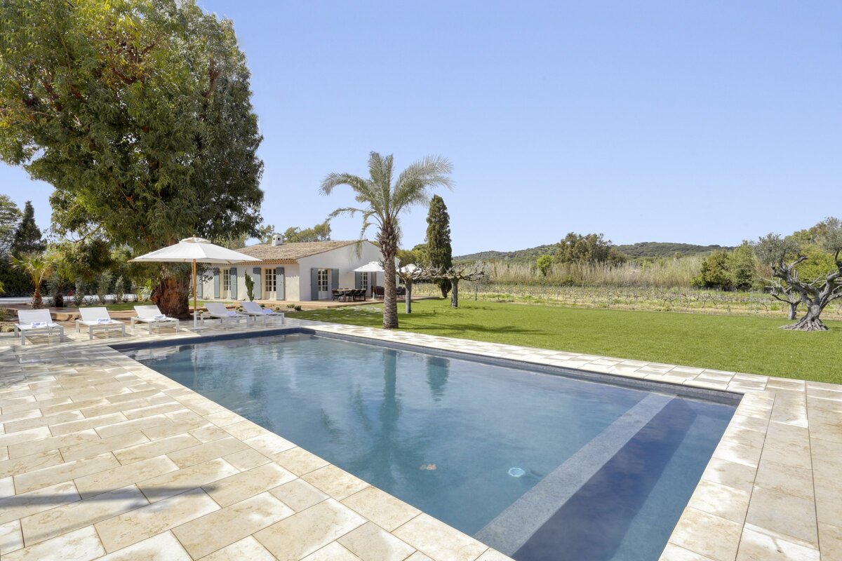A large swimming pool is surrounded by chairs and umbrellas