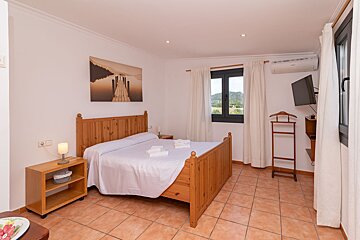 A bedroom with a painting on the wall above the bed