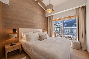 A bedroom with a large bed and a balcony