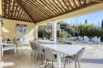 A white table and chairs under a wooden roof