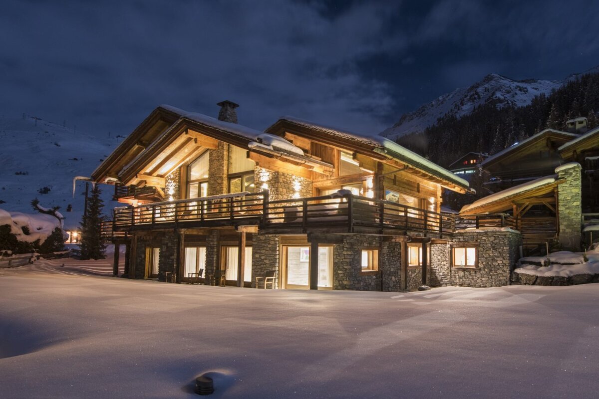 A large house is lit up in the snow at night