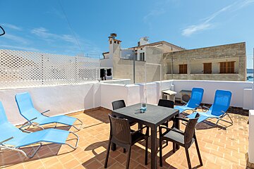 A patio with a table and chairs and blue lounge chairs