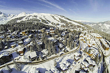 An aerial view of a snowy ski resort with mountains in the background